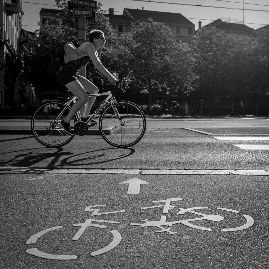 Cyclist riding on bike lane in Zurich city street, black and white urban photography