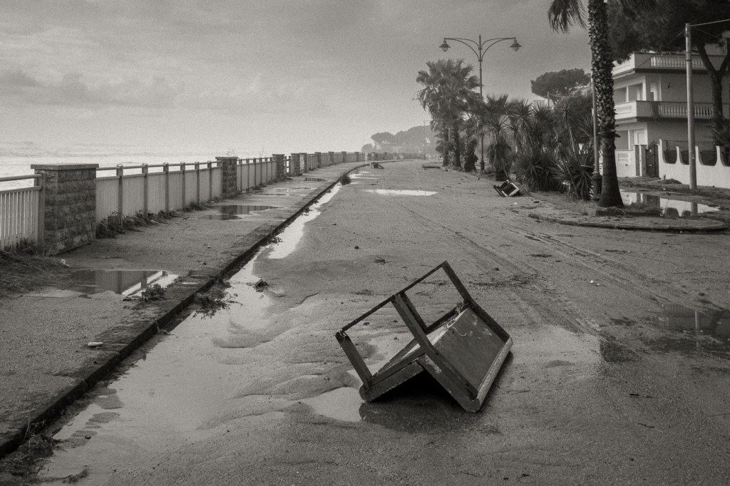 Flood-damaged coastal promenade in Brancaleone, Calabria, with overturned bench and storm debris