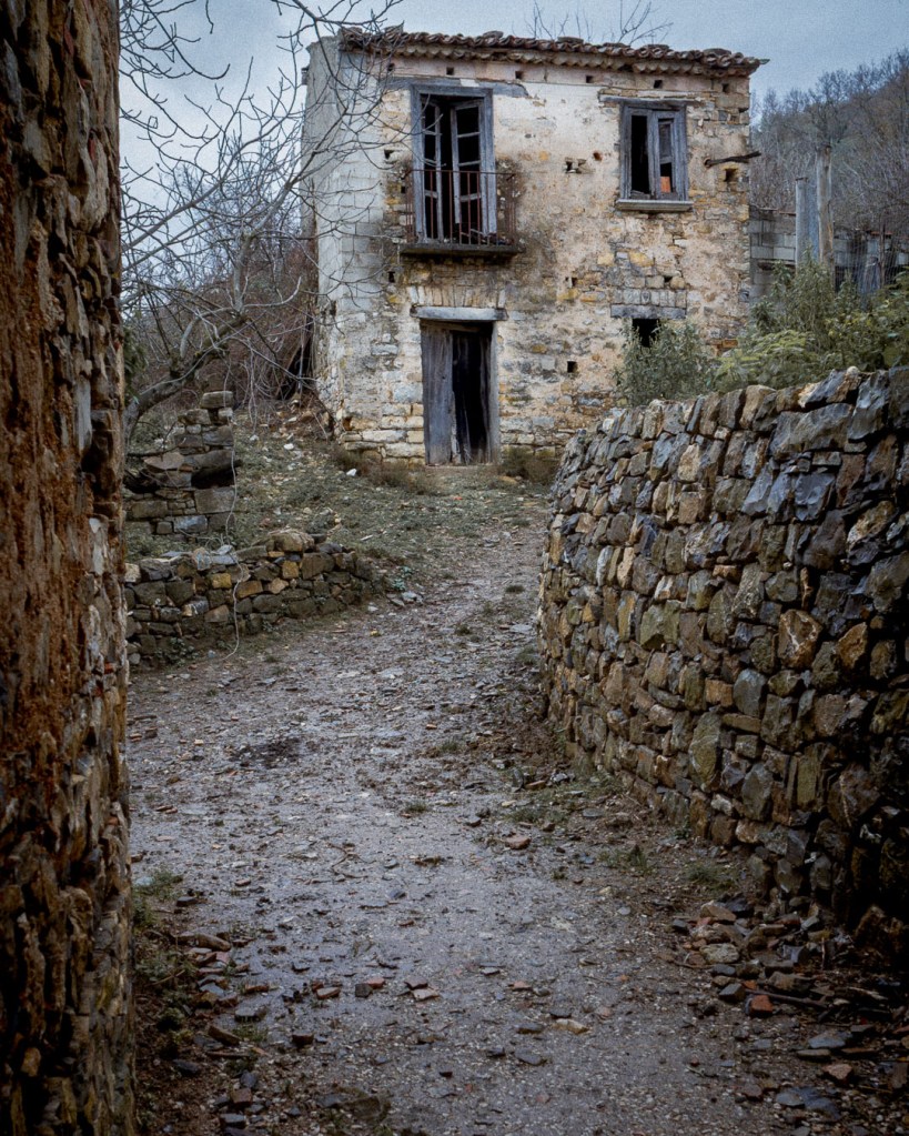 Narrow rural path leading to an abandoned stone house in Roscigno Vecchia, bordered by dry‑stone walls and winter vegetation. Roscigno Vecchia, Campania