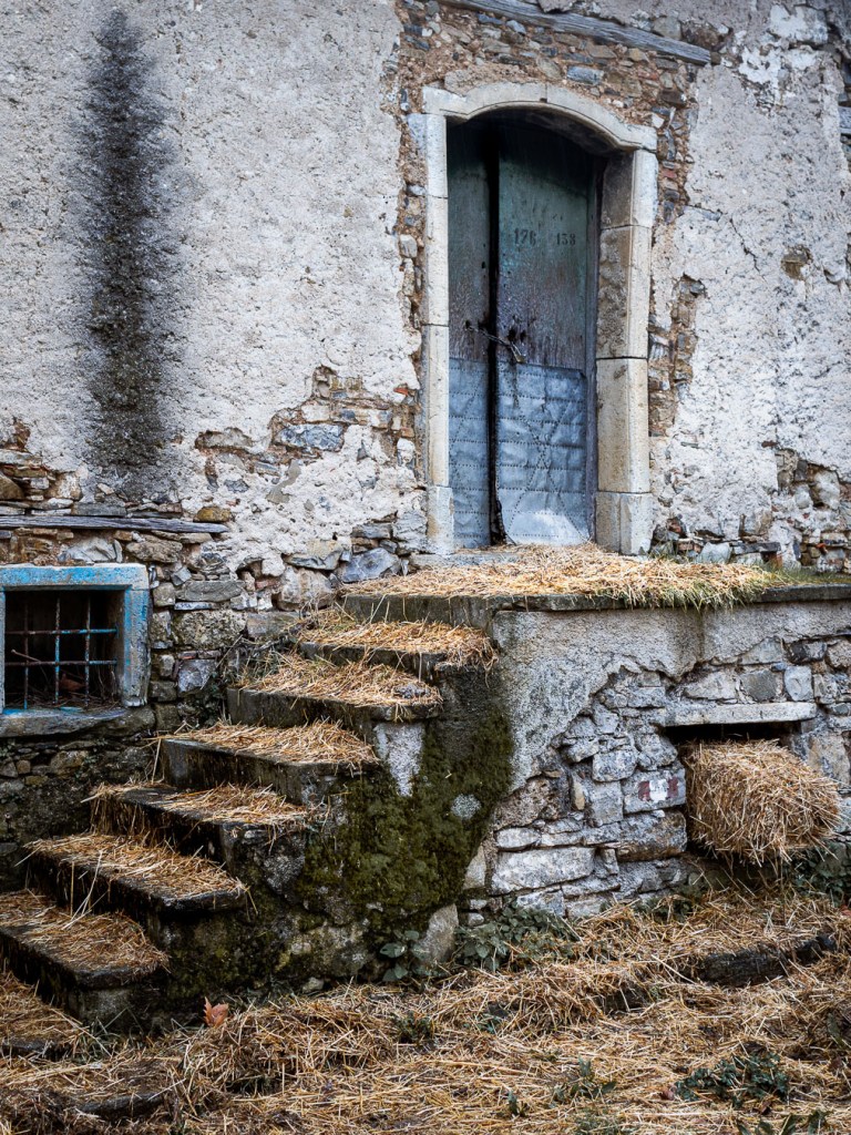 Old stone entrance of an abandoned house in Roscigno Vecchia, with worn steps, a closed wooden door, and rustic architectural details, Roscigno Vacchia, Campania