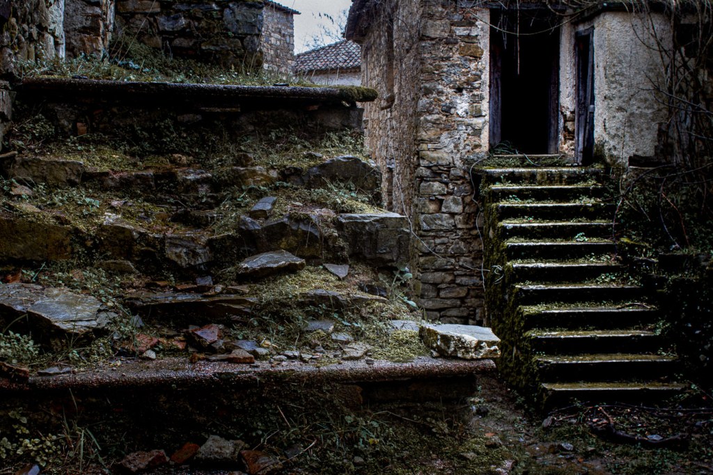 Weathered stone staircase leading to an abandoned building in Roscigno Vecchia, surrounded by overgrown vegetation, Roscigno Vecchia, Campania