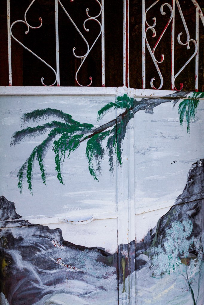 Fragment of a painted landscape mural below a decorative iron grille, Palizzi Superiore