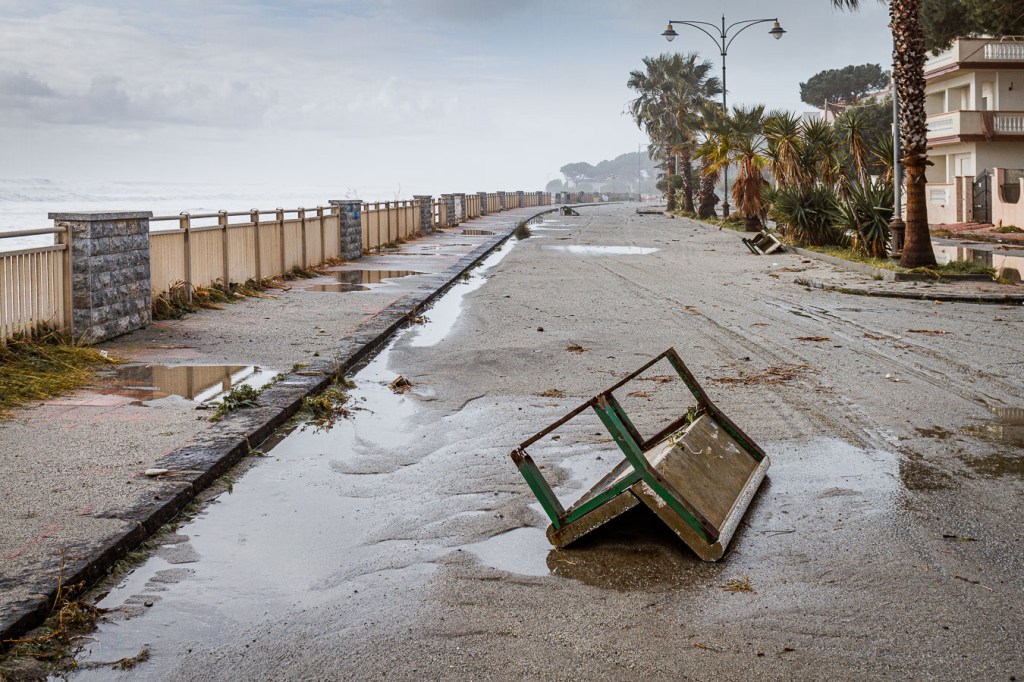 Flood-damaged coastal promenade in Brancaleone, Calabria, with overturned bench and storm debris, Brancaleone, Calabria
