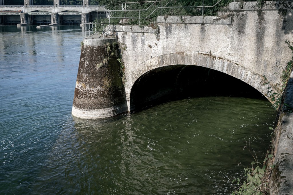 Concrete arch where the Glatt enters the Rhine; the arches of a barrage in the background to the left.